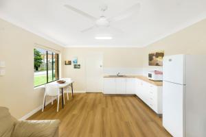 a white kitchen with a table and a refrigerator at Peninsula in Sawtell