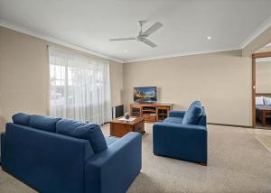a living room with two blue couches and a tv at Robys Retreat in Sawtell