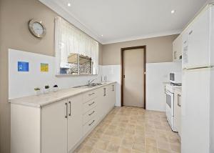 a kitchen with white cabinets and a white refrigerator at Robys Retreat in Sawtell