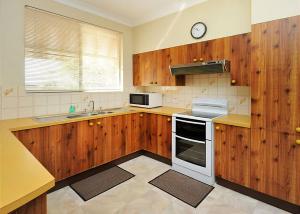 a kitchen with wooden cabinets and a stove top oven at Rose Cottage in Sawtell
