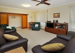 a living room with couches and a flat screen tv at Rose Cottage in Sawtell