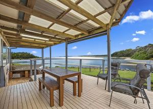 a wooden deck with a table and two chairs at Lobster Cottage in Sawtell