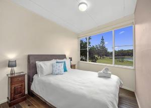 a bedroom with a bed and a large window at Lobster Cottage in Sawtell
