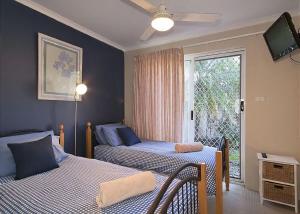 two beds in a room with a window and a tv at 1/17 22nd Ave - Sawtell, NSW in Sawtell