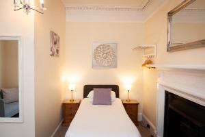 a bedroom with a bed with two lamps and a fireplace at Alban and Abbey House in Inverness