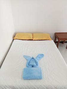 a white bed with a blue towel on it at Casa Leonora in Sabang