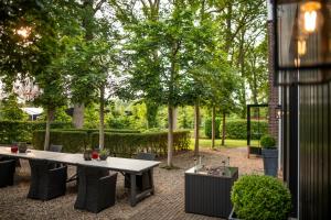 una mesa y sillas en un jardín con árboles en Koetshuis Landgoed Lauswolt, en Beetsterzwaag