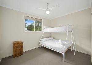 a white bunk bed in a room with a window at Sawtell Swells in Sawtell
