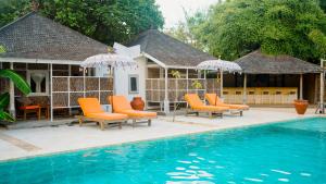 una piscina con sillas y sombrillas junto a una casa en Les Villas Ottalia Gili Meno en Gili Meno