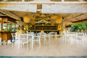 ein Esszimmer mit weißen Stühlen und einer Bar in der Unterkunft Les Villas Ottalia Gili Meno in Gili Meno