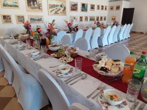 - une grande table avec des chaises blanches et de la nourriture dans l'établissement Gospoda Rycerska pod Grunwaldem, à Stębark