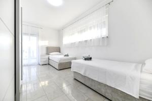 a white bedroom with two beds and a window at CROWONDER Villa Sunrise with Swimming Pool and Seaview in Vir