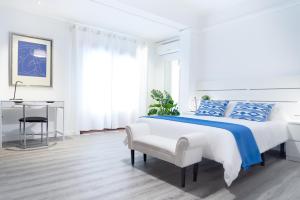 a white bedroom with a large bed and a chair at Veronica Beachfront Apartment by FESEAL in Port de Pollensa