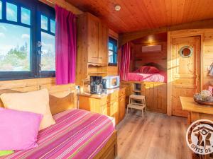 a bedroom with two beds in a wooden cabin at Roulotte climatisée avec piscine et jardin - FR-1-622-54 in Vihiers