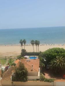 vistas a una casa y a la playa con palmeras en Spectacular renovated studio facing the sea, en Valencia