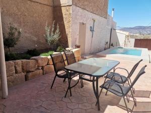 um pátio com uma mesa e cadeiras ao lado de uma piscina em CASA MOYA-LA ENCARNACIÓN em Caravaca de la Cruz