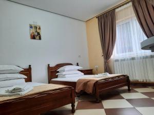 Una habitación de hotel con dos camas y una ventana. en Pensiunea Putnisoara, en Putna