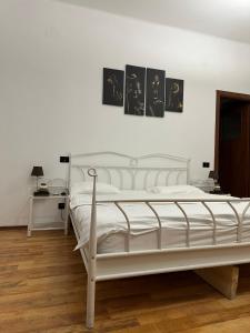 sypialnia z białym łóżkiem z dwoma obrazami na ścianie w obiekcie Casa Mendeleev w Bukareszcie