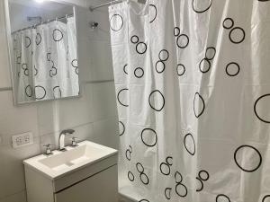 y baño con cortina de ducha y lavamanos. en 6-Maravilloso departamento morón centro en Morón