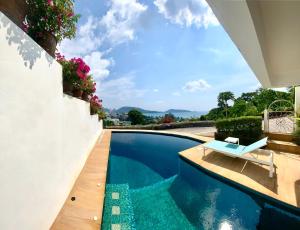 a swimming pool with a bench next to a house at Andaman Hill Pool Seaview in Patong Beach