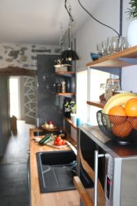 una cucina con una ciotola di arance e un forno a microonde di La Ferme Parrinet - Gîte et Chambres d'hôtes a Saint-Martin-Laguépie