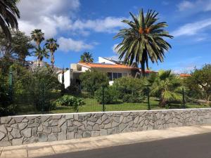 a house with palm trees and a stone wall at Casa Palmeira - Ferienhaus mit Meerblick in Caniço