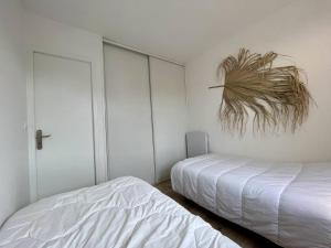 een slaapkamer met twee bedden en een plant aan de muur bij Appartement Saint-Georges-d'Oléron, 2 pièces, 4 personnes - FR-1-246A-222 in Saint-Georges-dʼOléron