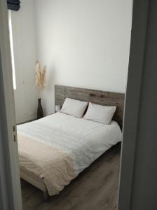 Schlafzimmer mit einem Bett mit weißer Bettwäsche und Kissen in der Unterkunft Appartement de charme bord de Loire in Saumur