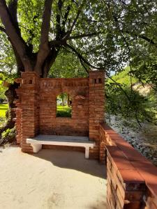 a brick wall with a bench under a tree at Casa Ele in Frăsinet