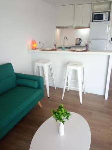 uma sala de estar com um sofá verde e uma cozinha em Apartamento nuevo, centrico y con vista a la bahia em Montevidéu