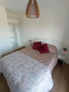 um quarto com uma cama com duas almofadas vermelhas em Apartamento nuevo, centrico y con vista a la bahia em Montevidéu