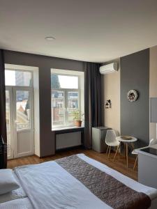 a bedroom with a bed and a table and two windows at Aparthotel Old Avenue in Tbilisi City