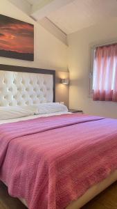 um quarto com uma cama grande e um cobertor rosa em Modus Vivendi - Room E Relax em Brisighella