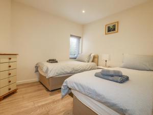 een slaapkamer met 2 bedden, een dressoir en een raam bij Falcon House in Tintagel