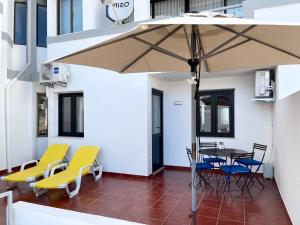 patio con tavolo, sedie e ombrellone di The Olive Tree Vilamoura Centre a Vilamoura