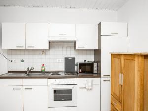 ツェル・アン・デル・モーゼルにあるFerienwohnungen Merlの白いキャビネット、シンク、電子レンジ付きのキッチンが備わります。