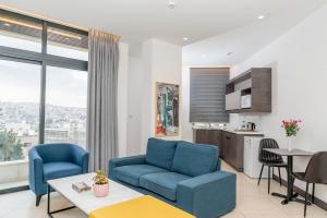 ein Wohnzimmer mit 2 blauen Stühlen und eine Küche in der Unterkunft Liv Weibdeh Hotel Suites in Amman