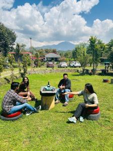 a group of people sitting in the grass at Dreamwoods A travellers farmhouse in Dharamshala