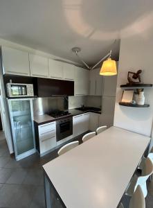 una cucina con tavolo bianco e armadietti bianchi di Appartamento in centro con terrazze e parcheggio gratuito a Lignano Sabbiadoro