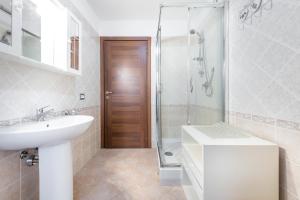 y baño blanco con lavabo y ducha. en Villetta Bacio del Sole, en Sinnai
