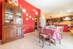 a kitchen with a table and a red wall at Villetta Bacio del Sole in Sìnnai +18 photos
