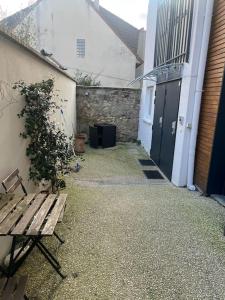 an empty alley with a wooden bench next to a building at Charm'in Champigny: Studio cosy, détente & travail in Champigny-sur-Marne