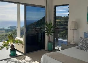 a bedroom with a view of the ocean at Belvedere in Kororo Basin