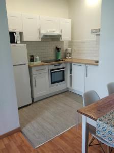 eine Küche mit weißen Geräten und einem Tisch mit Stühlen in der Unterkunft Appartement calme proche de la Loire in Saumur