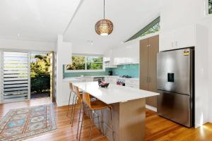 Una cocina con refrigerador y una mesa con sillas. en 1 38 Boronia St, en Sawtell