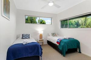 Dos camas en una habitación con dos ventanas. en 1 38 Boronia St, en Sawtell