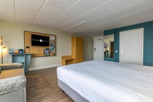 een slaapkamer met een groot bed en een televisie bij Fletcher Hotel Restaurant Loosdrecht-Amsterdam in Loosdrecht