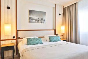 a bedroom with a large bed with two blue pillows at Atlantic Hôtel & Spa in Les Sables-d'Olonne