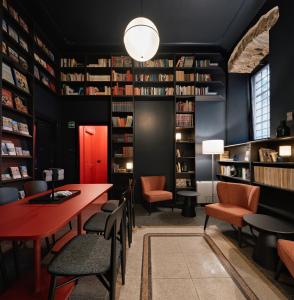 a library with a red table and chairs and bookshelves at URBANAUTS STUDIOS Minelli in Trieste