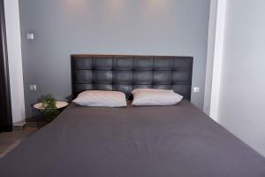 a bed with a black leather headboard and two pillows at Florina Sky Loft in Florina